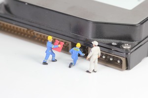 Minuature plastic men working on a close up hard drive