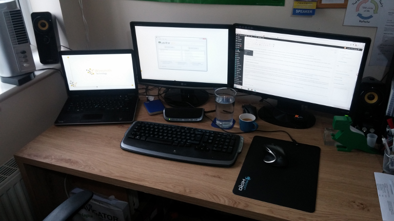Image of a desk with two monitors and an open laptop